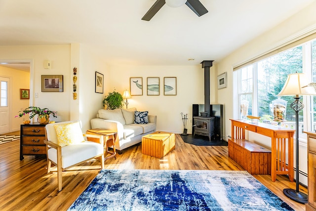 living room featuring hardwood / wood-style floors, a wood stove, and ceiling fan