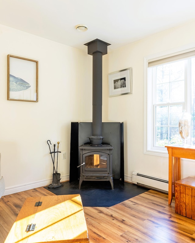 interior details with hardwood / wood-style flooring, a wood stove, and baseboard heating