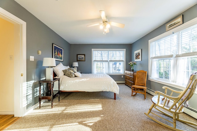 bedroom featuring ceiling fan, light hardwood / wood-style floors, a baseboard radiator, and multiple windows