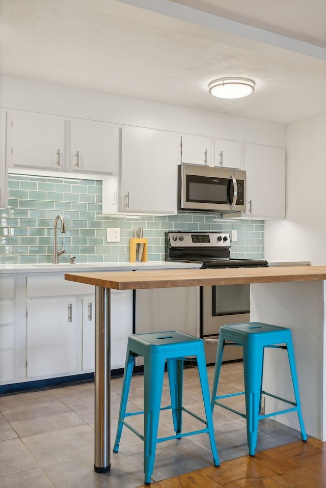 kitchen with a breakfast bar area, white cabinetry, and stainless steel appliances