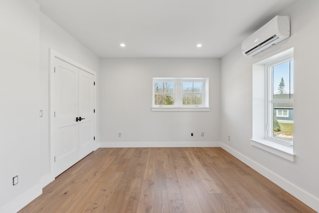 43 Rose Douglas Ln, Brunswick, ME 04011 - unfurnished bedroom featuring baseboards, multiple windows, light wood-style floors, and a wall mounted air conditioner