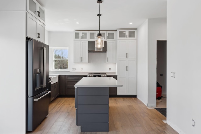 43 Rose Douglas Ln, Brunswick, ME 04011 - kitchen featuring a center island, wall chimney exhaust hood, light countertops, high end black fridge, and light wood finished floors