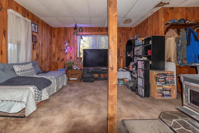 bedroom with carpet flooring, a drop ceiling, and wooden walls