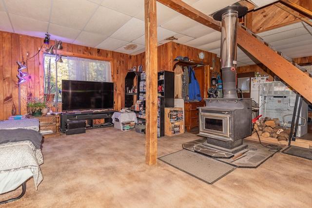 basement featuring carpet, a wood stove, and wooden walls