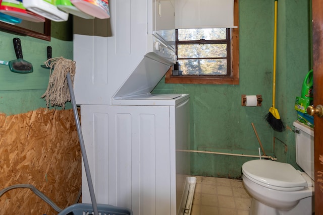 bathroom with toilet and stacked washer / drying machine