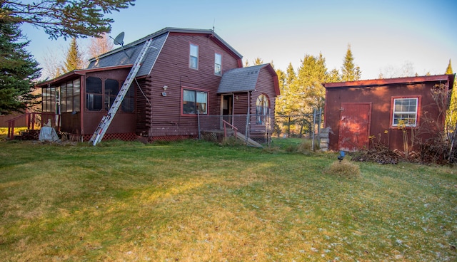 back of property with a lawn, a sunroom, and a storage shed