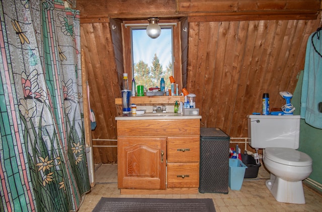 bathroom with vanity, wood walls, and toilet