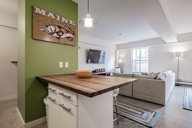 kitchen featuring white cabinetry, hanging light fixtures, a kitchen breakfast bar, wooden counters, and a baseboard heating unit