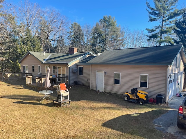 rear view of house featuring a wooden deck, a yard, and a garage