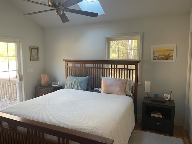 bedroom with hardwood / wood-style floors, ceiling fan, and vaulted ceiling with skylight