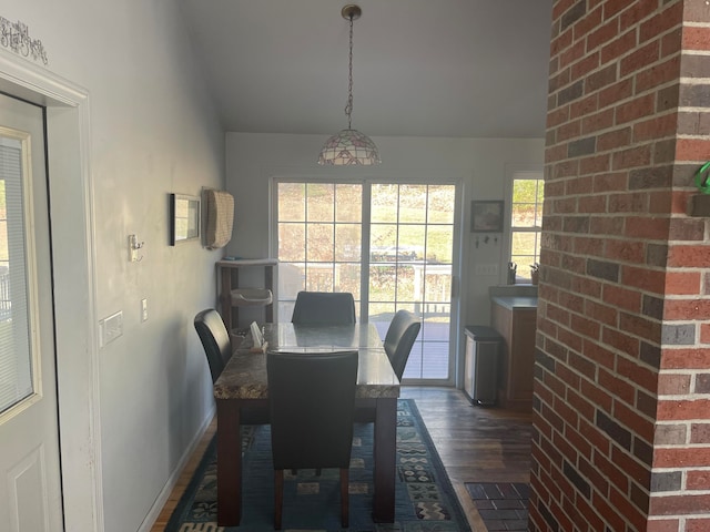 dining area with dark hardwood / wood-style flooring and brick wall