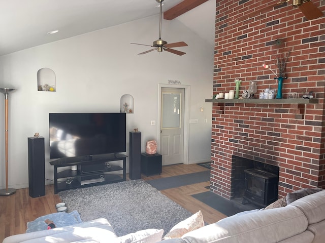 living room featuring a wood stove, high vaulted ceiling, light hardwood / wood-style flooring, ceiling fan, and beam ceiling