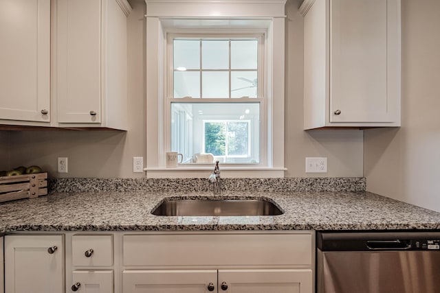 kitchen with white cabinets, light stone counters, stainless steel dishwasher, and sink