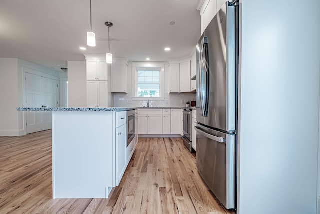 kitchen featuring sink, hanging light fixtures, light hardwood / wood-style floors, white cabinets, and appliances with stainless steel finishes