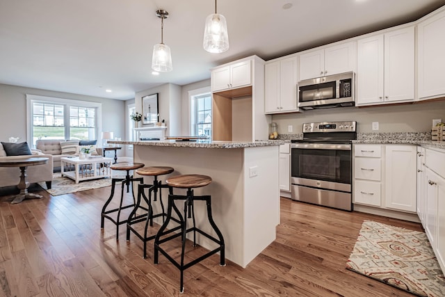 kitchen featuring white cabinets, appliances with stainless steel finishes, a kitchen island, and hardwood / wood-style floors