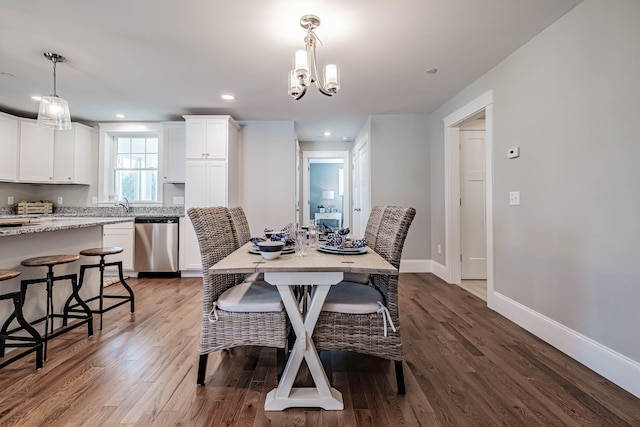 dining area with wood-type flooring, a notable chandelier, and sink