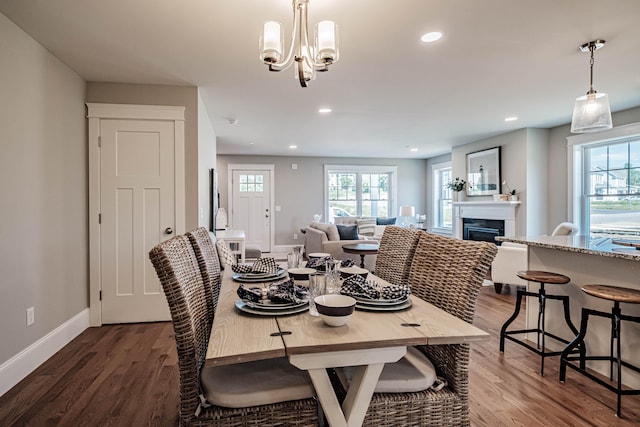 dining space with a wealth of natural light, dark wood-type flooring, and an inviting chandelier