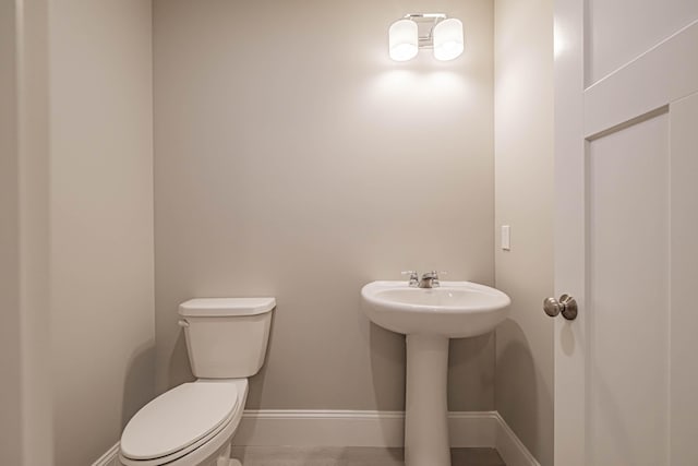 bathroom with toilet, sink, and tile patterned floors