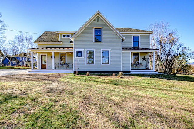 rear view of house featuring a yard and covered porch