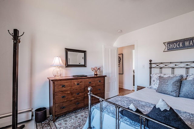 bedroom featuring hardwood / wood-style flooring, lofted ceiling, and baseboard heating