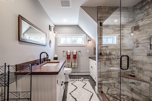 bathroom with toilet, vanity, a shower with shower door, and a baseboard heating unit