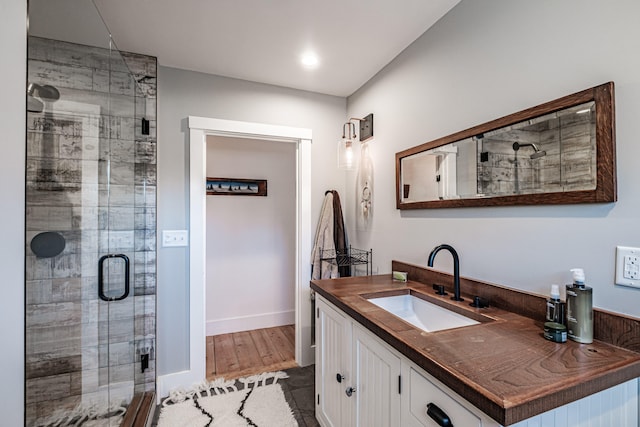 bathroom with wood-type flooring, vanity, and a shower with shower door