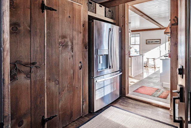 kitchen featuring hardwood / wood-style flooring, crown molding, and stainless steel refrigerator with ice dispenser