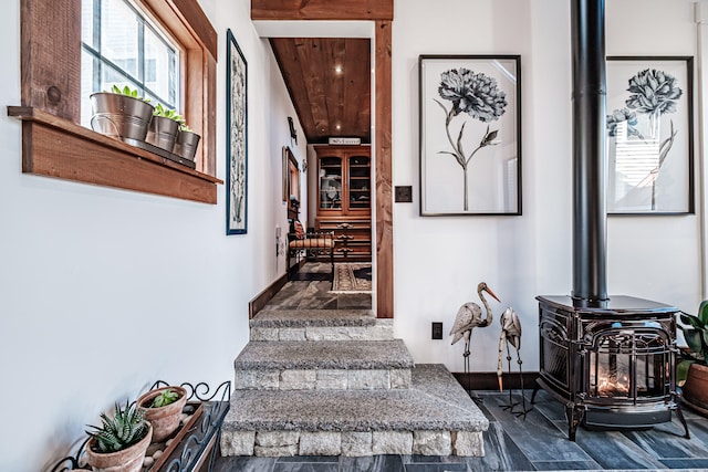 stairway with a wood stove, hardwood / wood-style floors, and wood ceiling