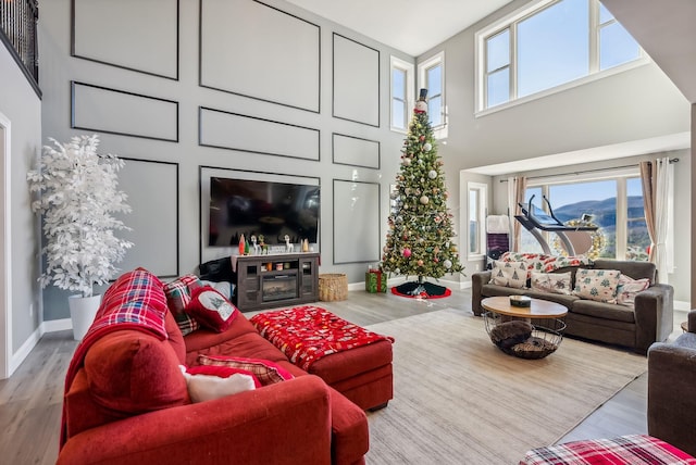 living room featuring a fireplace, a towering ceiling, and light hardwood / wood-style floors