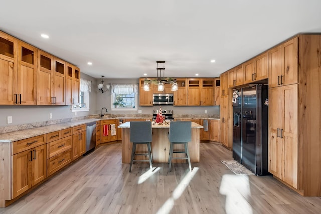 kitchen with a center island, light wood-type flooring, decorative light fixtures, a kitchen bar, and stainless steel appliances