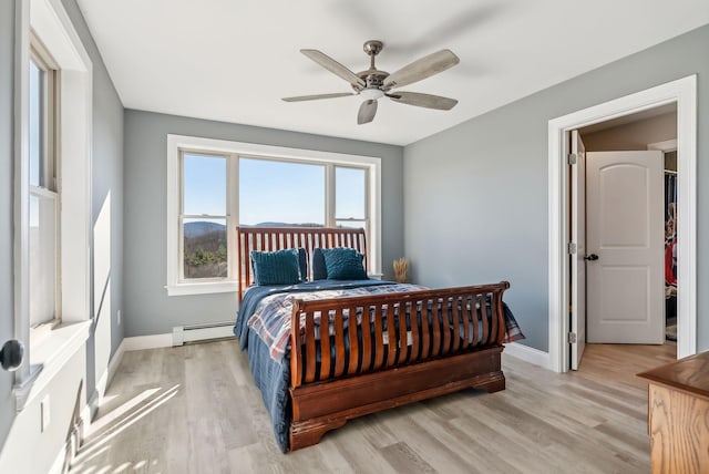 bedroom featuring baseboard heating, ceiling fan, and light wood-type flooring