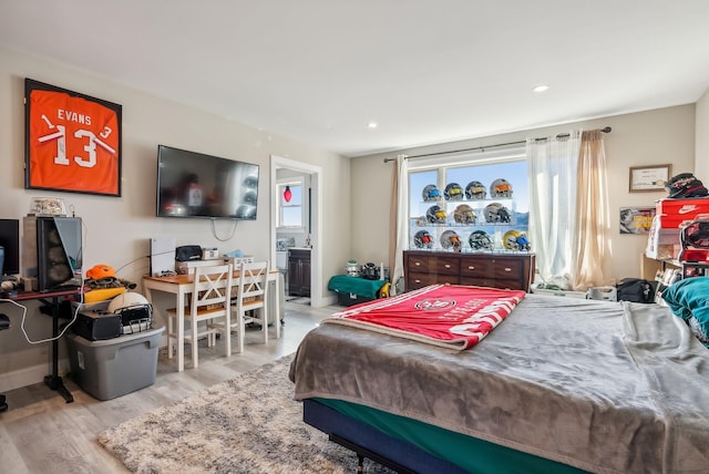 bedroom featuring connected bathroom and light hardwood / wood-style flooring