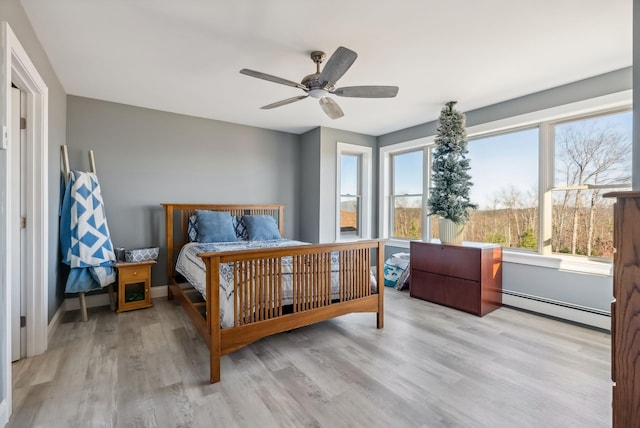 bedroom with light wood-type flooring, baseboard heating, and ceiling fan