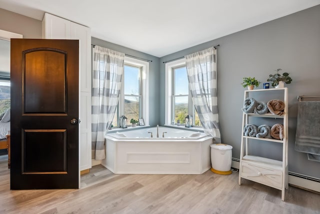 bathroom featuring hardwood / wood-style floors, a baseboard radiator, and a washtub