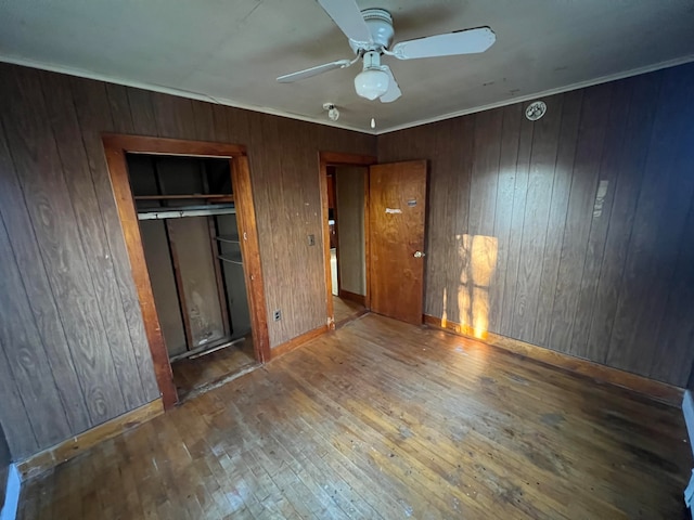 unfurnished bedroom featuring hardwood / wood-style floors, ceiling fan, and wooden walls