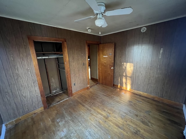 23 Hillcrest Ave, Millinocket, ME 04462 - unfurnished bedroom with hardwood / wood-style floors, wooden walls, a closet, baseboards, and ceiling fan