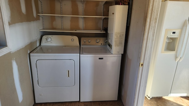 clothes washing area with wood-type flooring, separate washer and dryer, and water heater