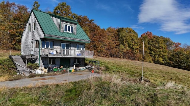 back of property featuring a deck and a lawn