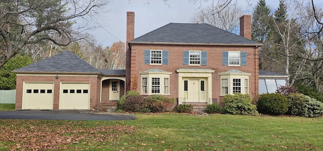 colonial inspired home featuring a garage and a front lawn