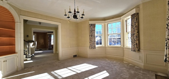 unfurnished room featuring carpet flooring, ornamental molding, and a notable chandelier