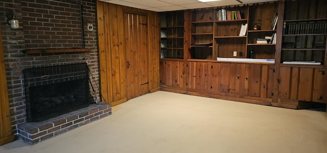 living room featuring a paneled ceiling, wood walls, and a fireplace