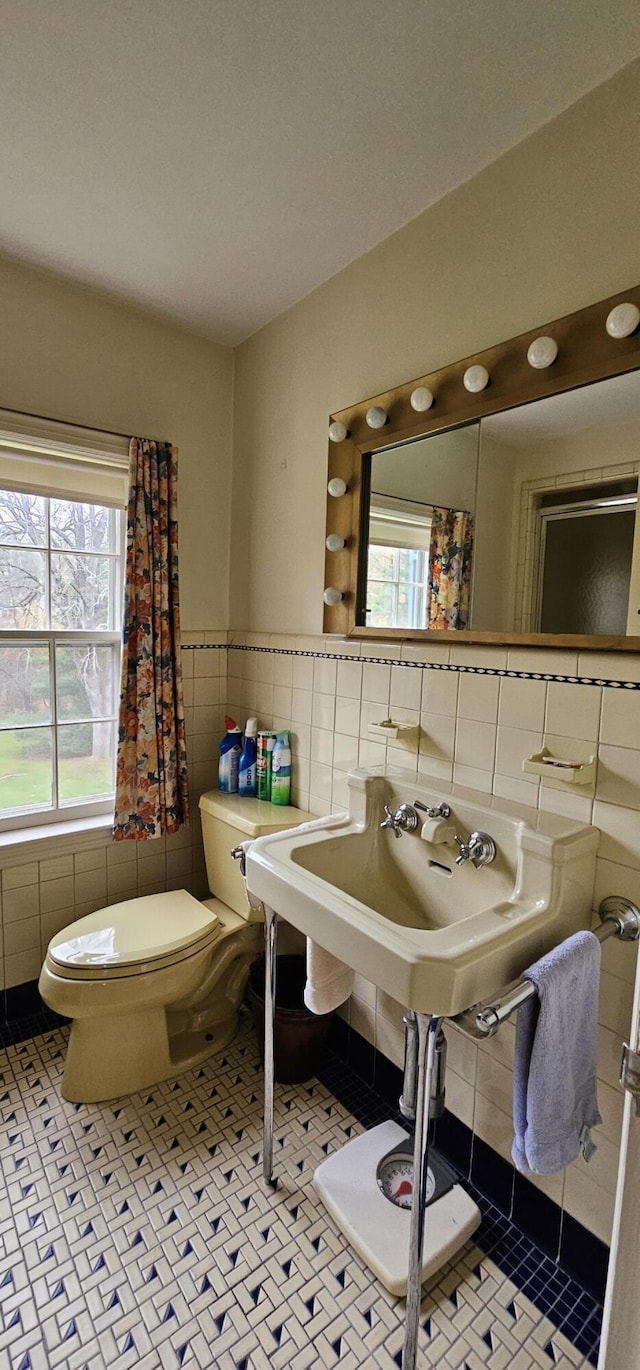 bathroom with a healthy amount of sunlight, tile walls, and toilet