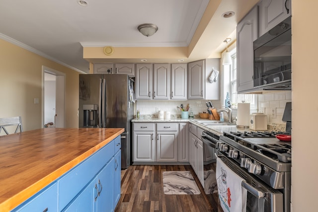 kitchen featuring dark wood-type flooring, sink, ornamental molding, butcher block countertops, and stainless steel appliances