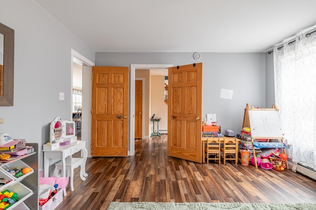 game room with dark hardwood / wood-style flooring and a baseboard heating unit