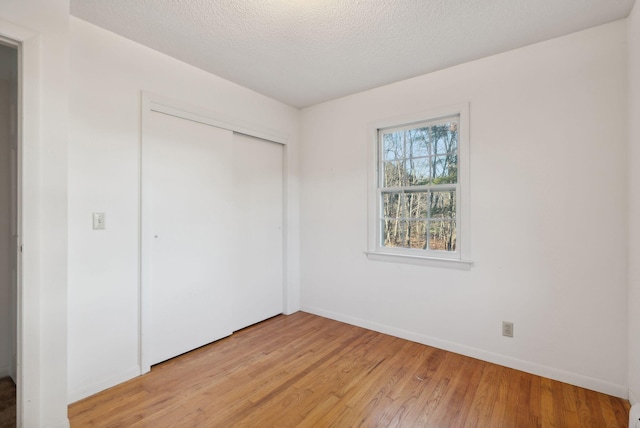 unfurnished bedroom featuring a closet, a textured ceiling, and light wood-type flooring