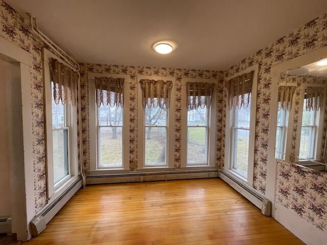 unfurnished sunroom featuring a baseboard heating unit