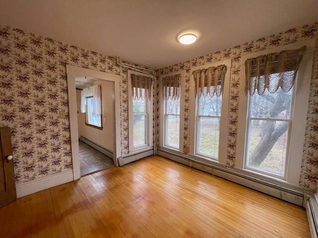 spare room with hardwood / wood-style flooring and a baseboard heating unit