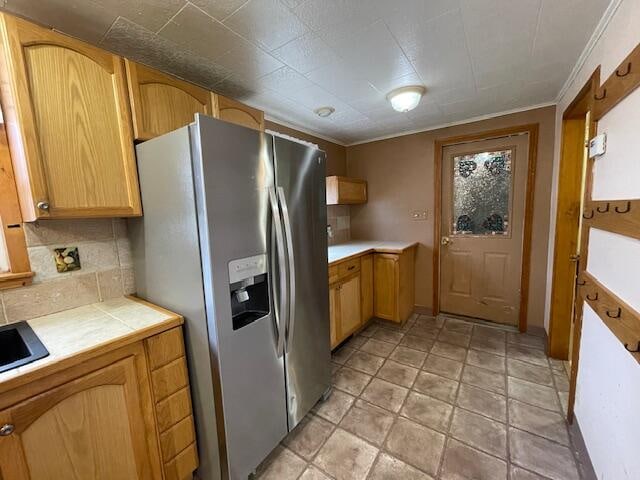 kitchen with decorative backsplash, stainless steel refrigerator with ice dispenser, and ornamental molding