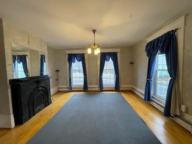 unfurnished living room featuring a chandelier, a fireplace, a wealth of natural light, and light hardwood / wood-style flooring