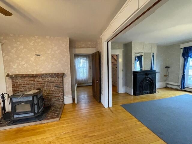 living room featuring light hardwood / wood-style floors, a wood stove, and ceiling fan